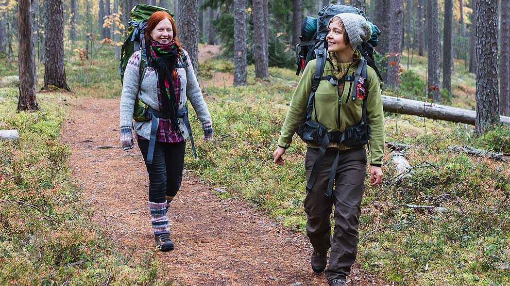 Två vandrare går längs stigen med ryggsäckar på ryggen.