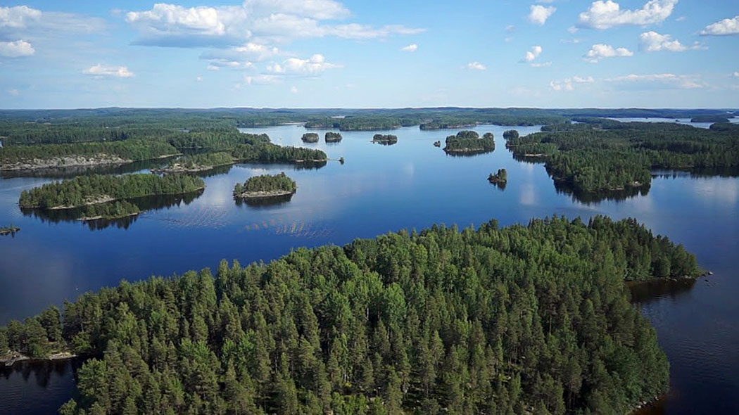 Ett flygfotografi av ett sjölandskap med många skogbeklädda öar. Flera av öarnas stränder är klippiga.