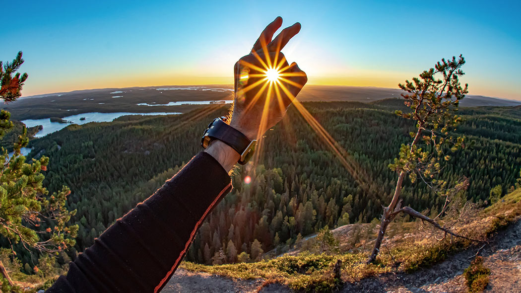 Vandraren har gjort ett OK-tecken med fingrarna runt solen.